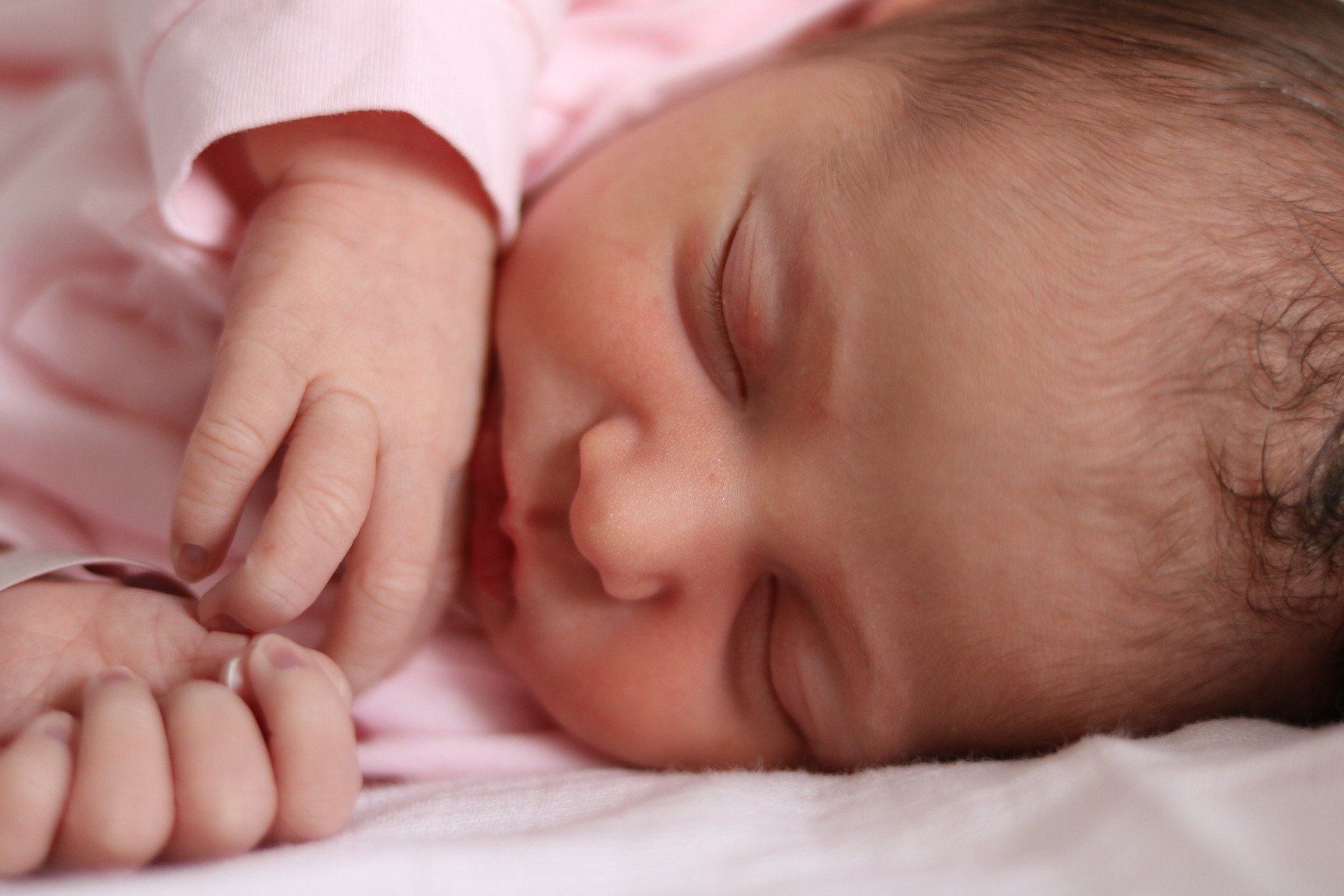 Petite fille habillée en rose et endormie sur un lit